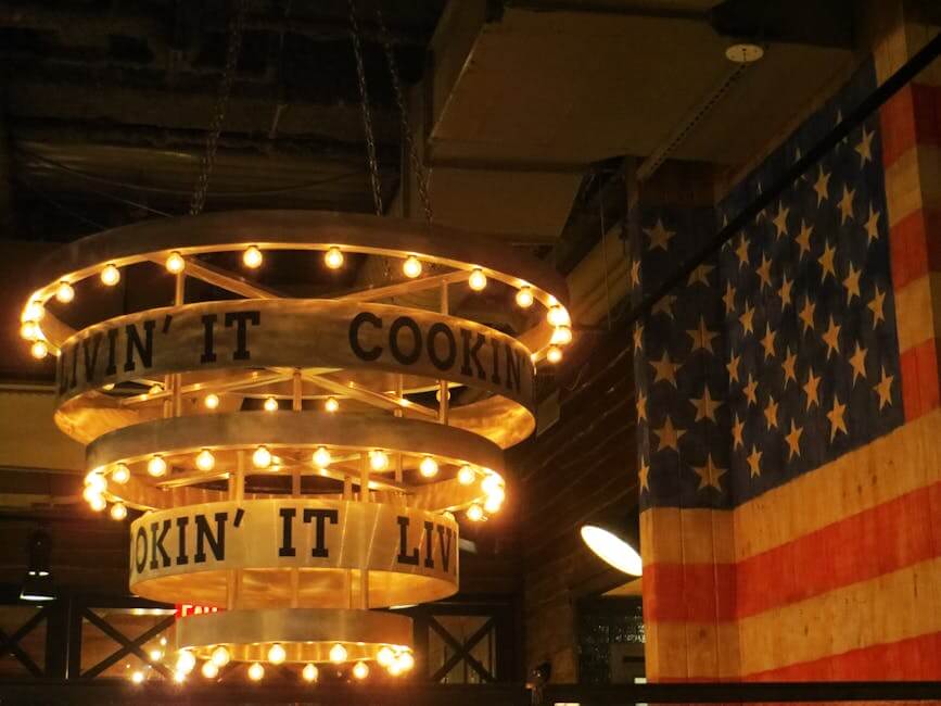 Cozy indoor restaurant setting with chandelier lights and American flag backdrop.